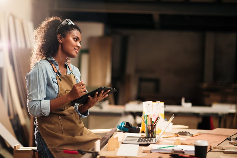 Young attractive african american female carpenter in wood working in small business workshop. Wood  industry and furniture industrial.