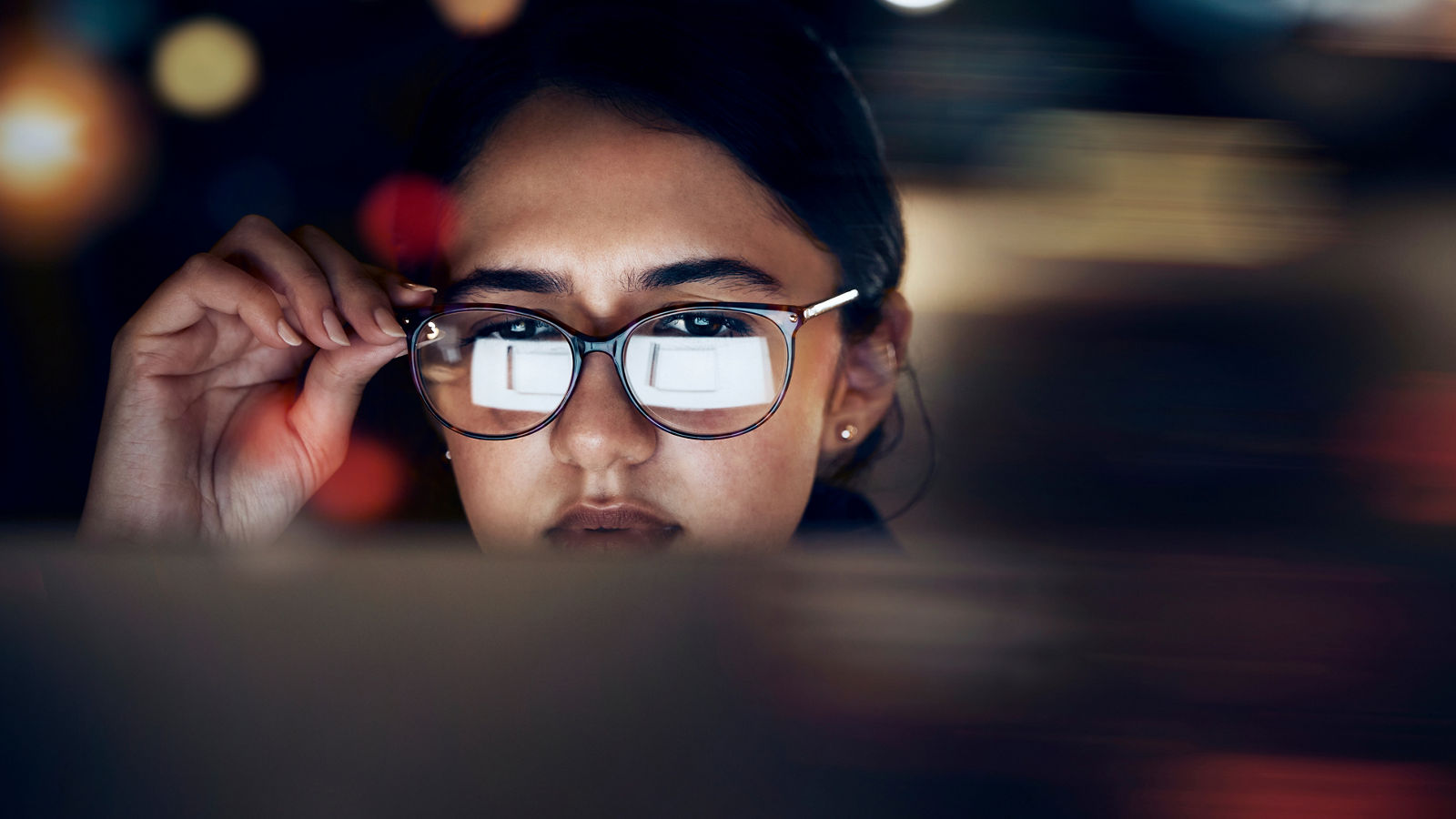 Woman, glasses reflection and computer at night for planning, website search and technology. Face of female working late on desktop, dark office and reading online network, focus vision and internet.