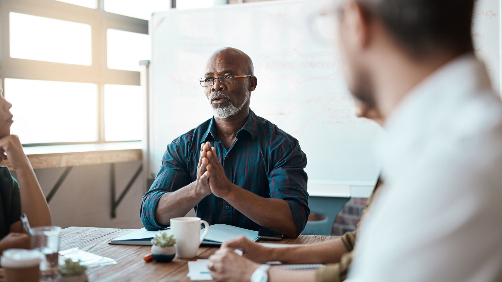 Business people, meeting leader and black man in office, talking or speaking. Teamwork, ceo and serious senior African male professional brainstorming, collaboration or planning group strategy.