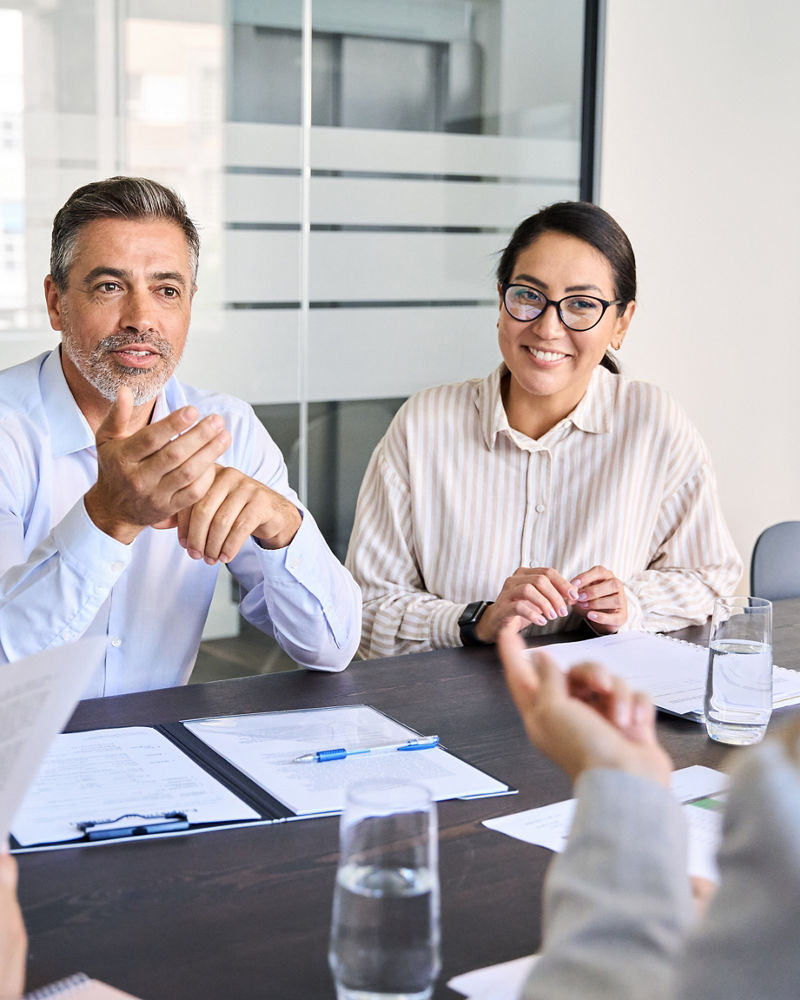 Diverse professional executive team working at meeting in office. Mid aged business man manager leader talking to board people consulting partners investors discussing project management in teamwork.