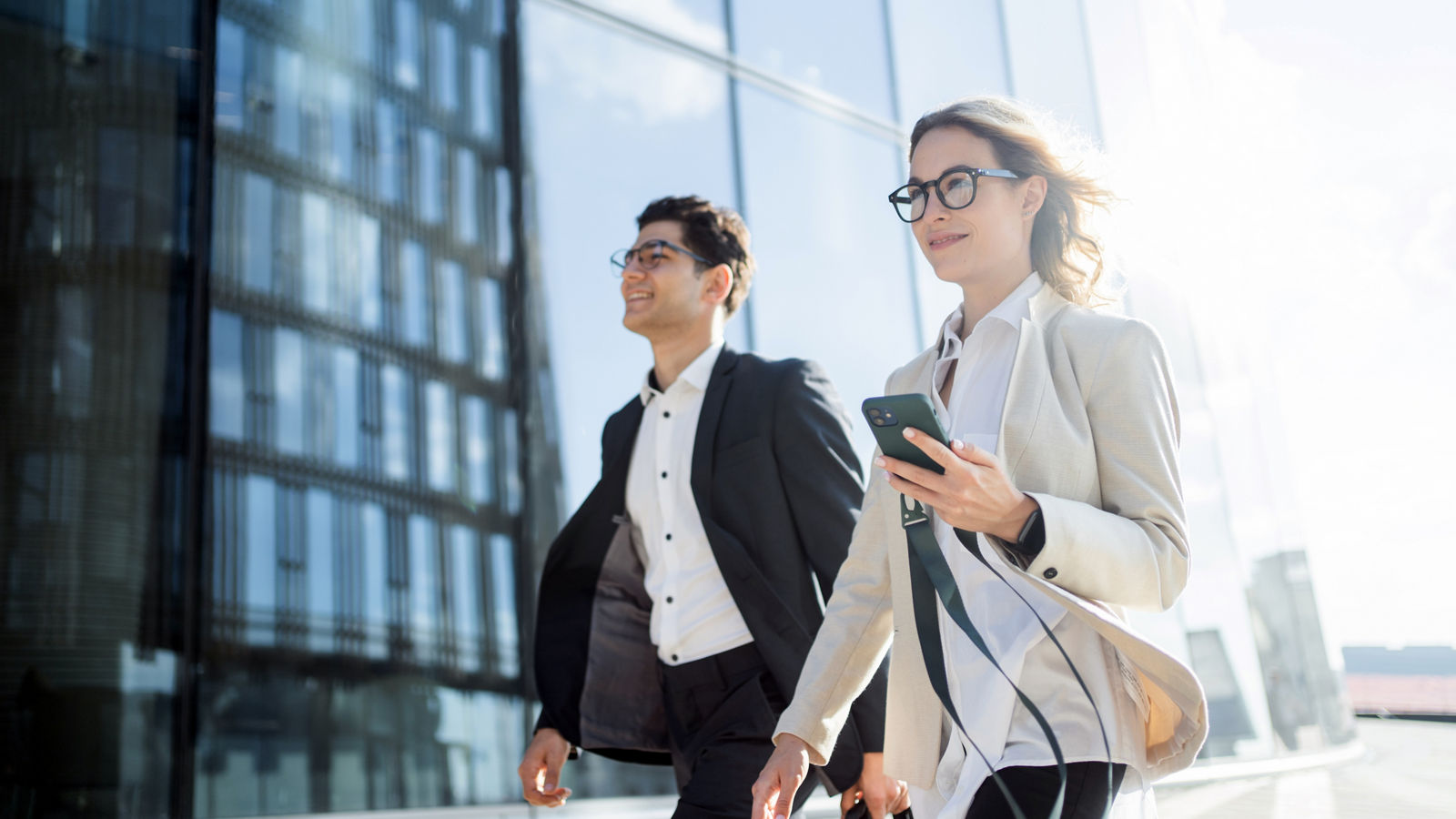A young team of programmers or financiers in glasses go to the office business meeting a woman and a man people in business clothes smile .