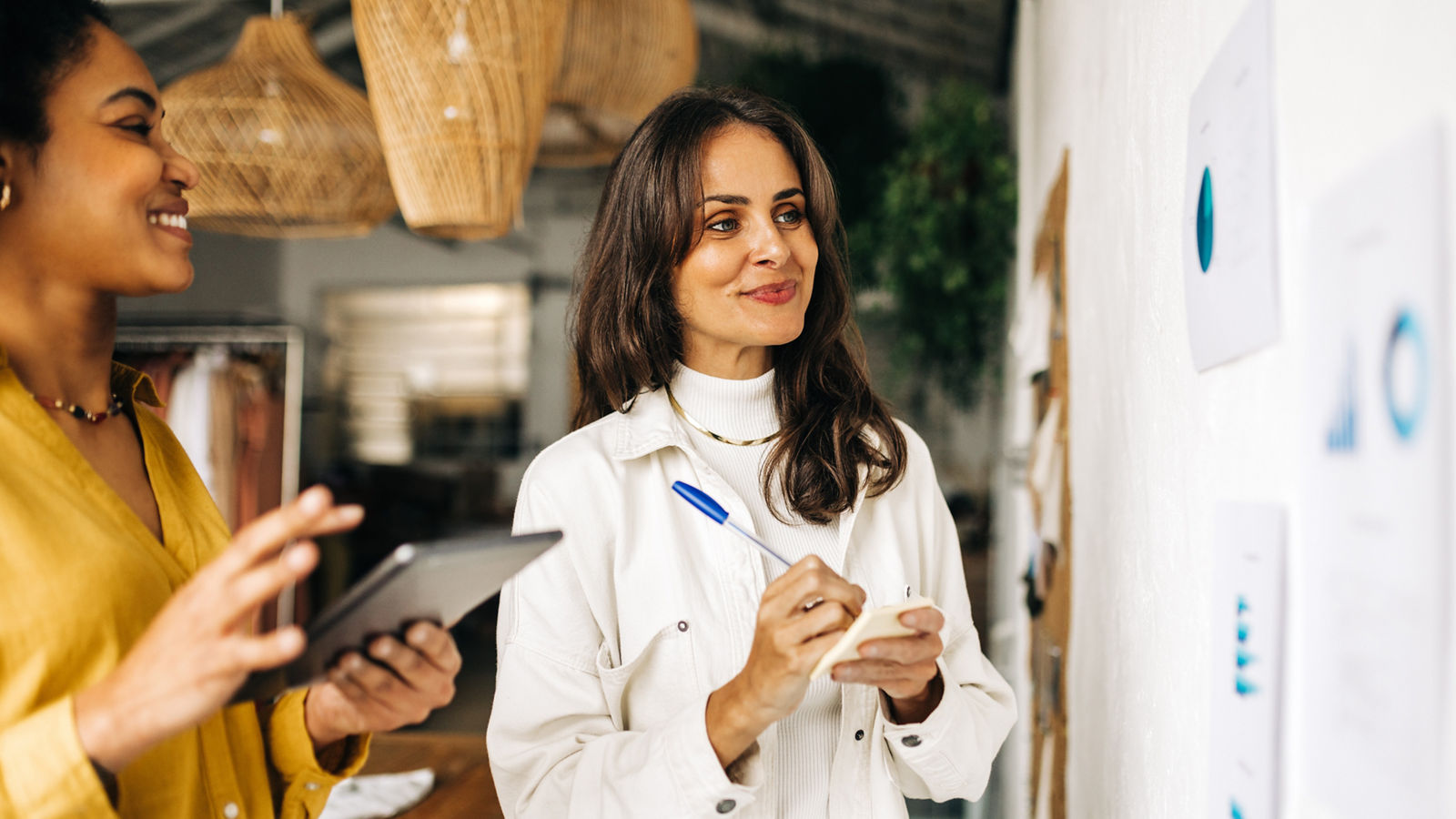With smiles on their faces, two business women brainstorm ideas for their business in an office. Working as a team, they collaborate to achieve their entrepreneurial goals and success.