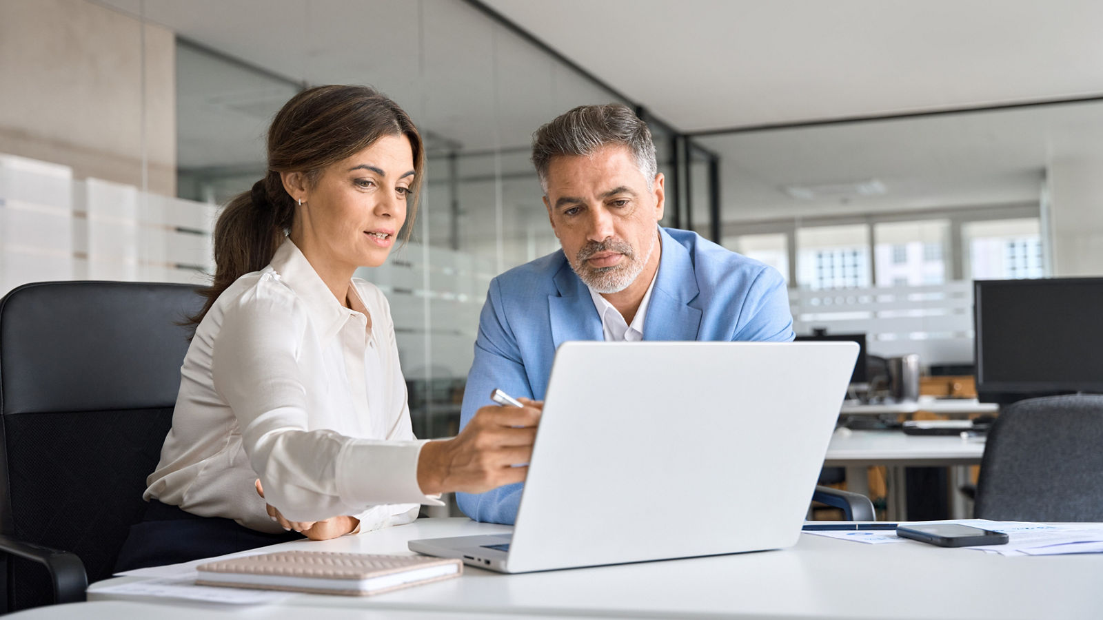 Two busy professional executive team business people working together on business finances analysis looking at computer at office meeting. Professional manager consulting corporate client using laptop