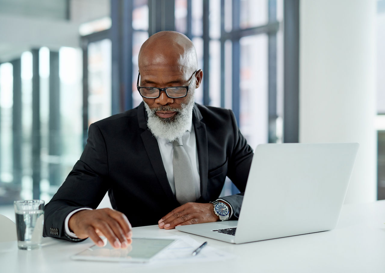 Businessman working on a laptop and digital tablet in an office