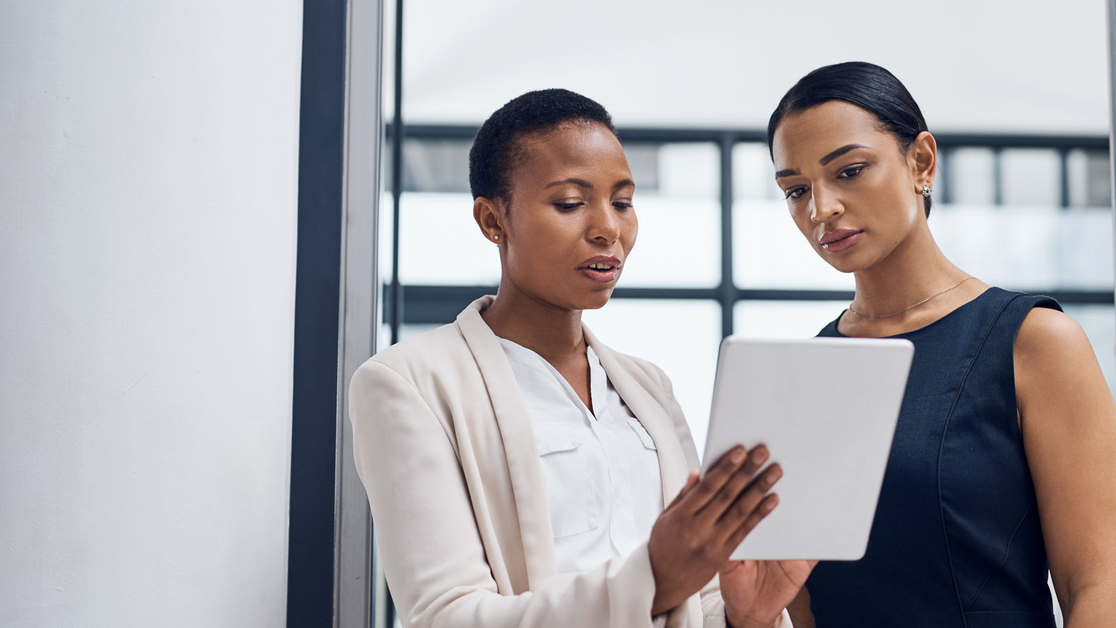 Shot of two businesswomen using a digital tablet together in a modern office