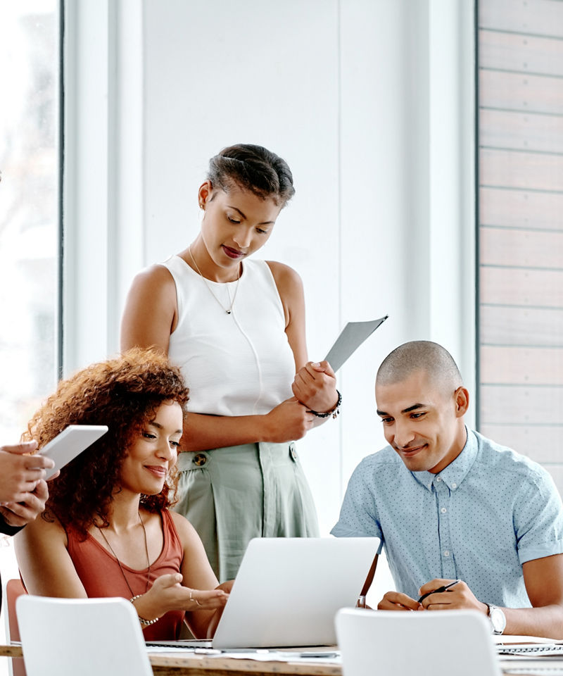 A group of businesspeople using a laptop together in their office