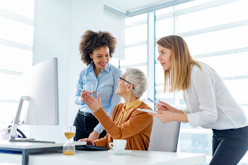 Coworkers looking at a computer and discussing over the new business plan