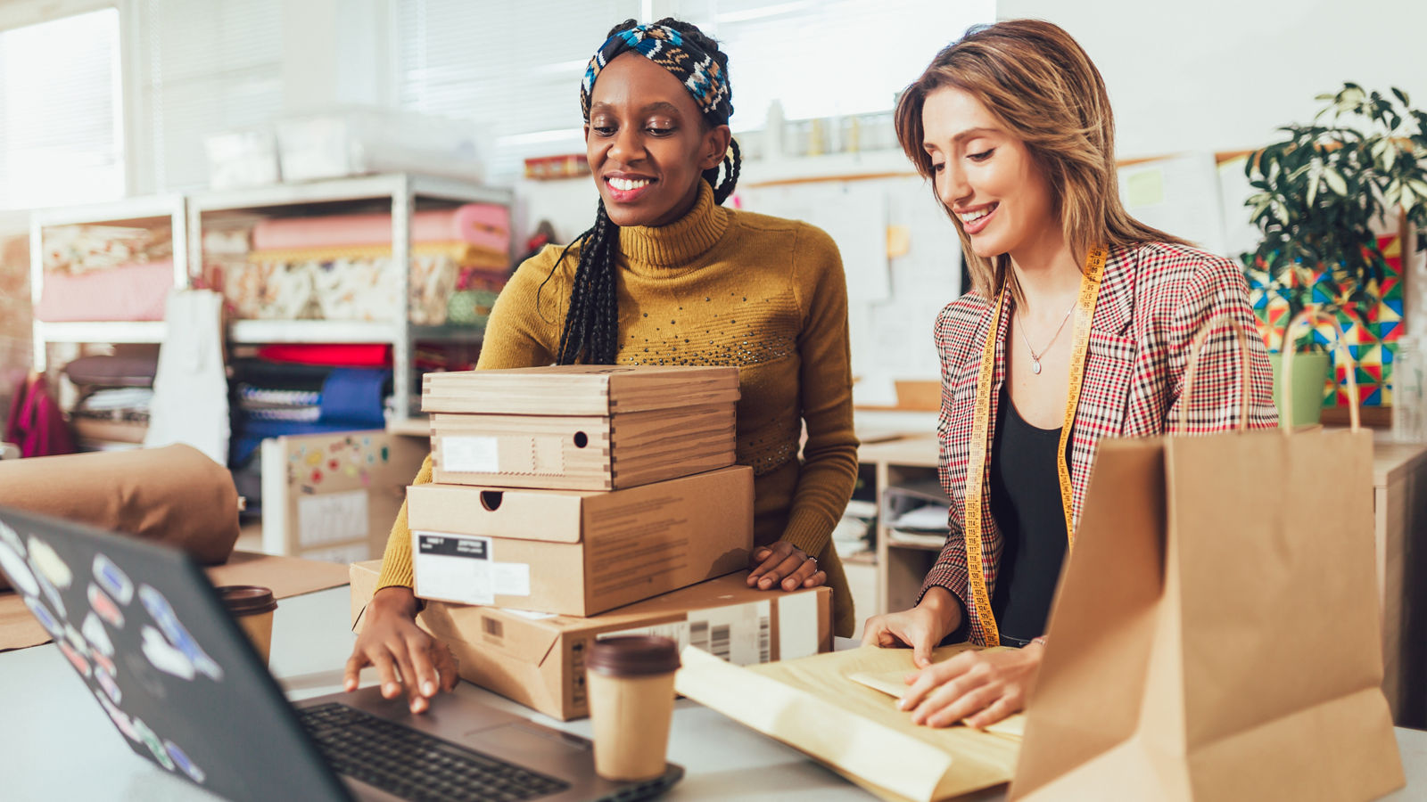 Women working inside of their small fashion business looking at computer