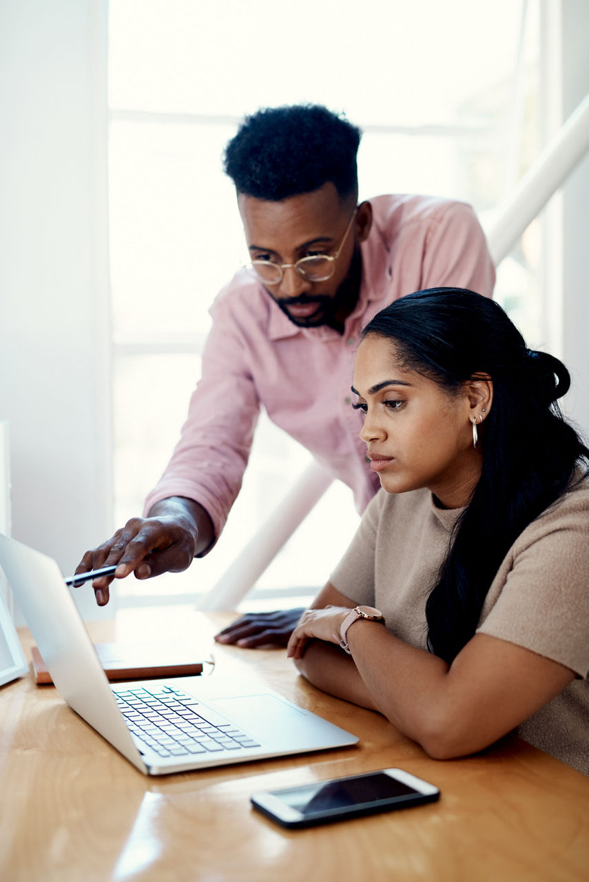 Two young businesspeople sitting in the office and working on a laptop together