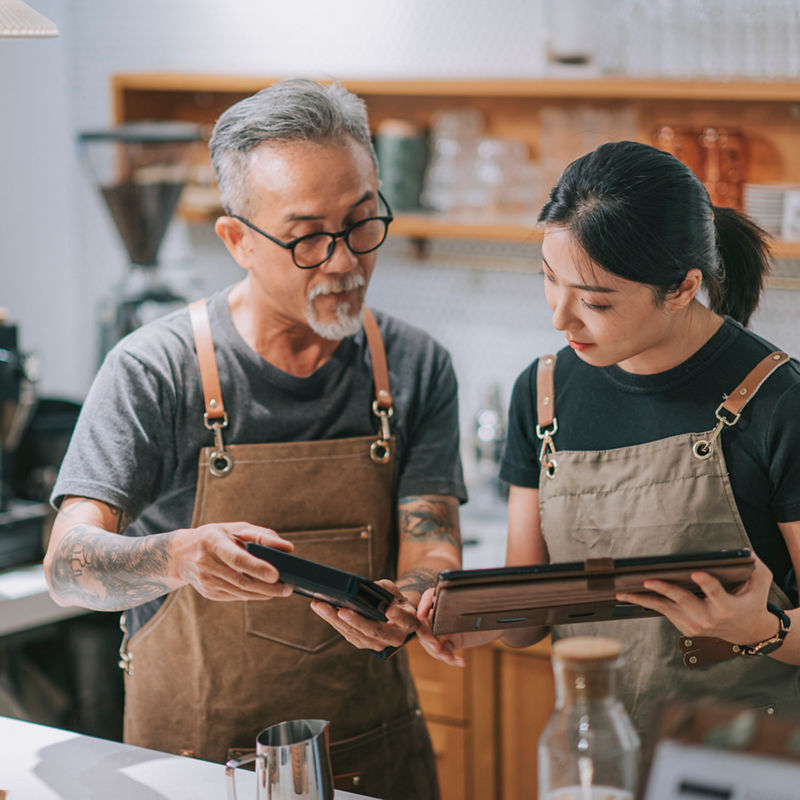 Small business owners looking at tablet in coffee shop