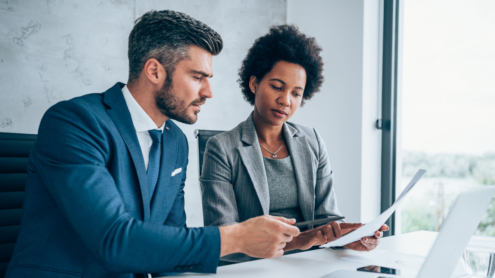 Two colleagues talking together while sitting in a modern office.