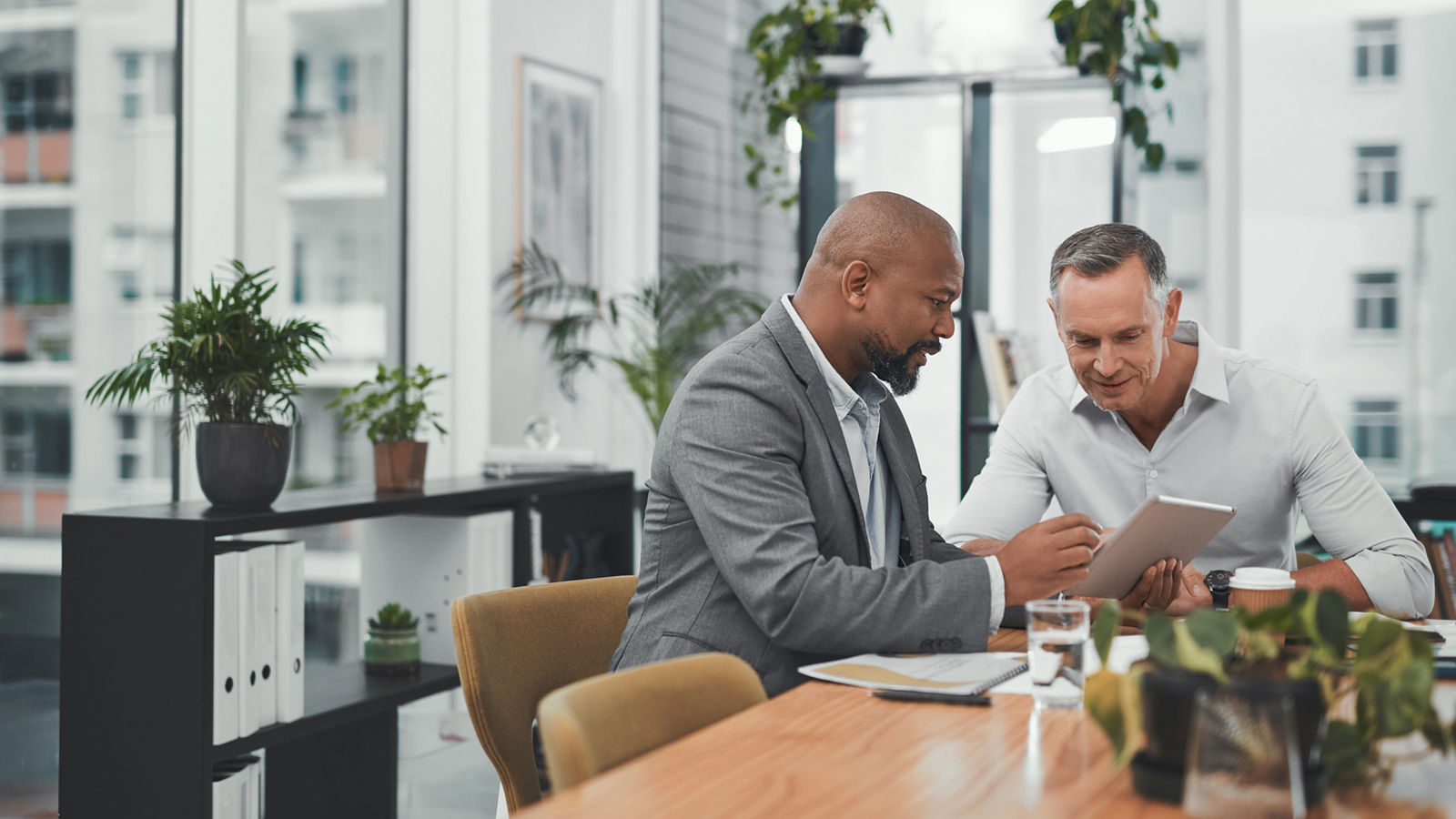 Two financial workers sitting at desk looking at tablet