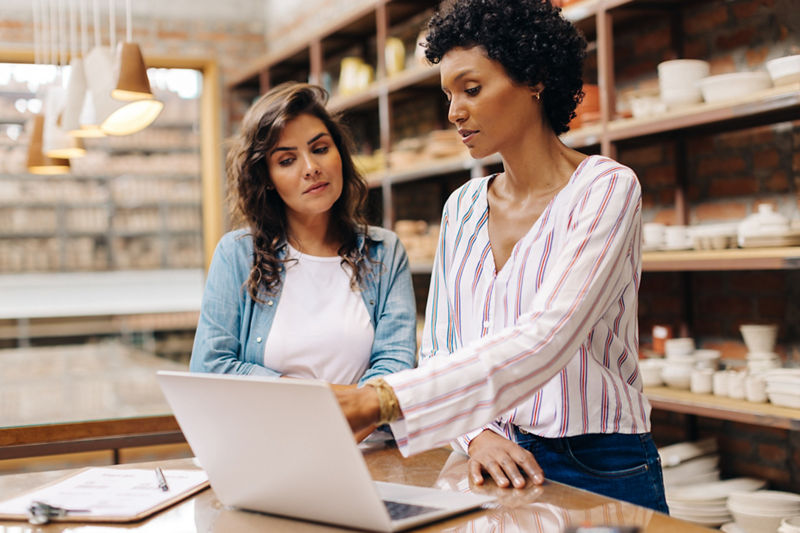 Young businesswomen using a laptop while working together in their ceramic store