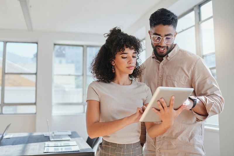 Coworkers looking at tablet planning strategy in office
