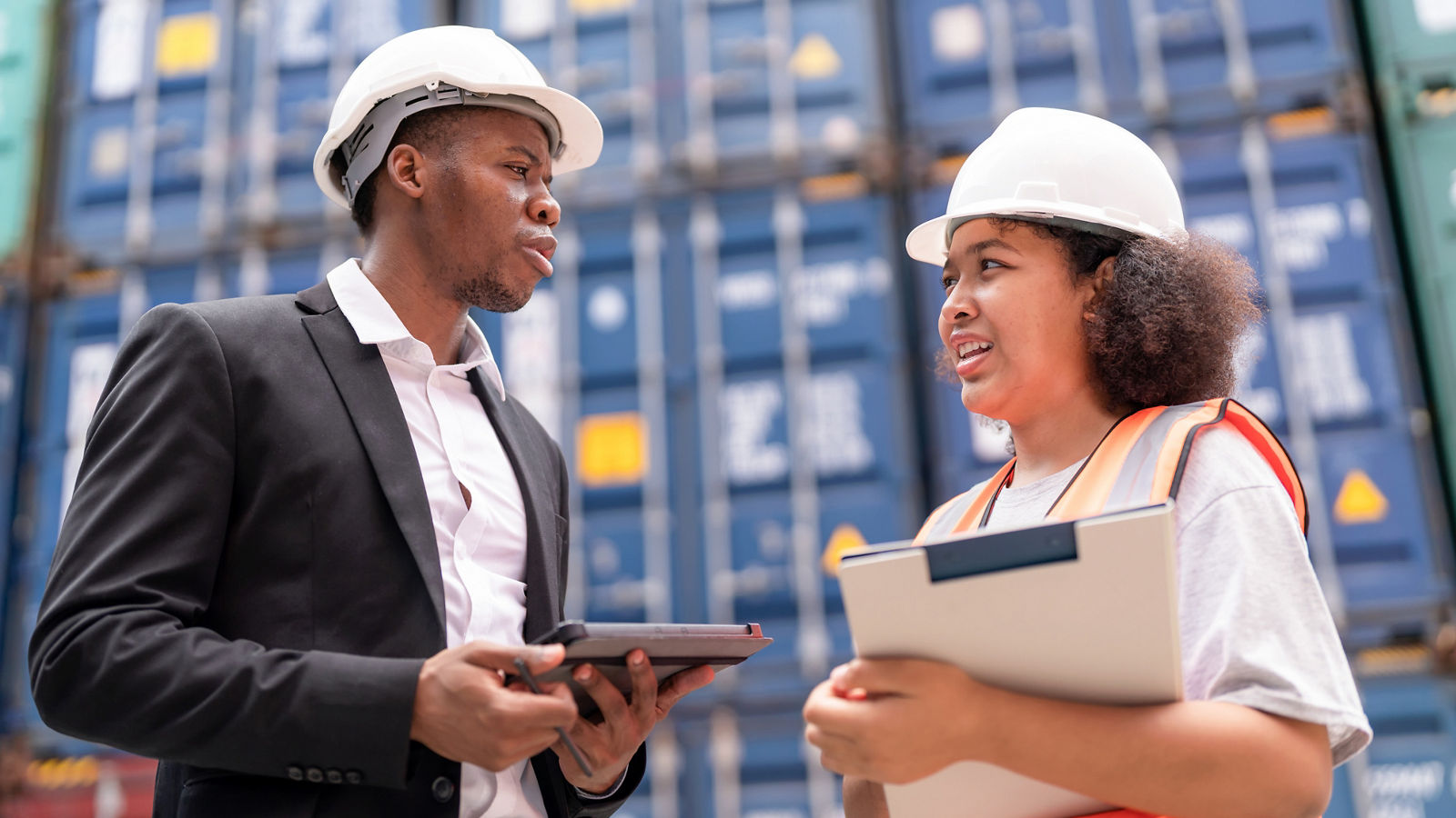 Dock manager standing and discussed over a tablet with engineer worker in shipment yard