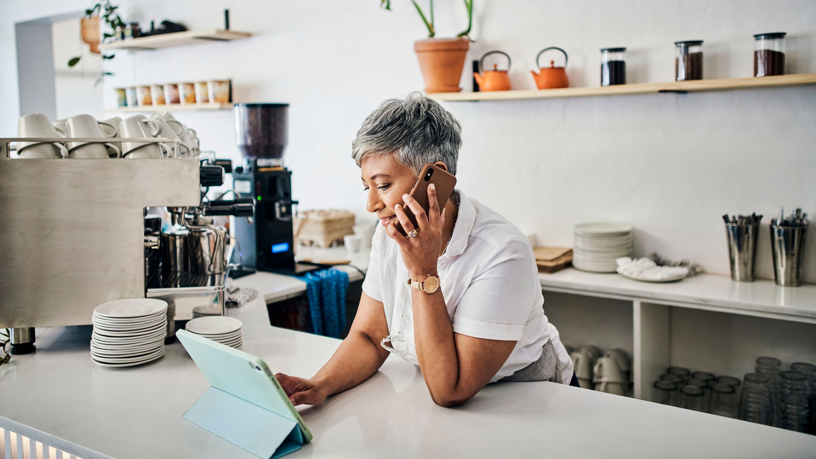 Woman in coffee shop, small business with tablet and phone