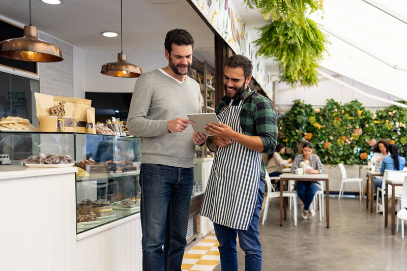 Waiter at a cafe showing a menu to a customer on a tablet computer
