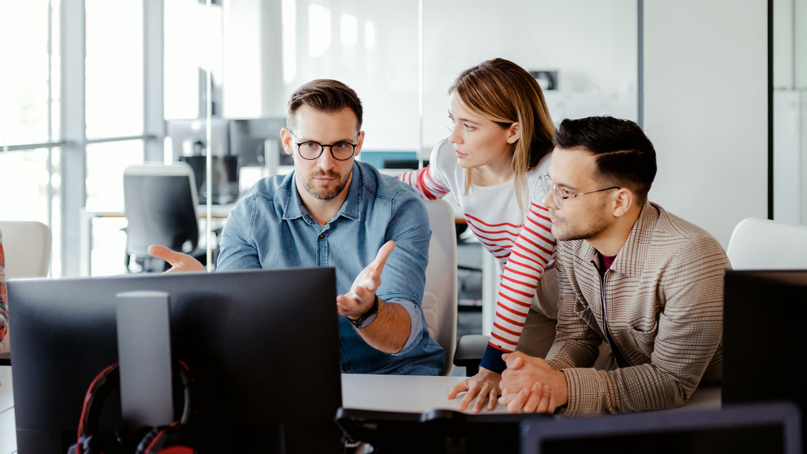 Team of programmers brainstorming around computer