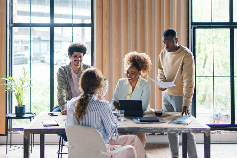 A group of cheerful business people gathered around the table having a meeting or a brainstorm session