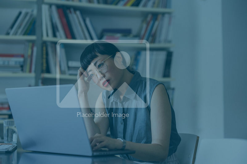 An upset Japanese entrepreneur reading something on her laptop while missing some deadline.  She is sitting at her office desk.