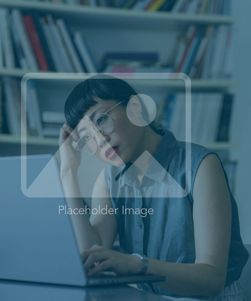 An upset Japanese entrepreneur reading something on her laptop while missing some deadline.  She is sitting at her office desk.