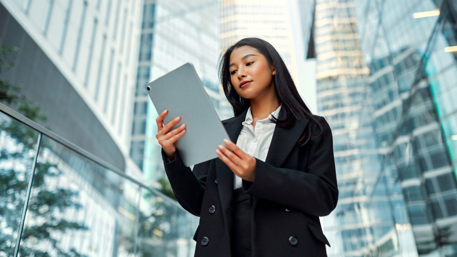 Businessman is sitting in an office and having a meeting with a female colleague. He might be working from home. It's morning or later in the day. He is smiling. A laptop is in front of him and the woman is holding a digital tablet.