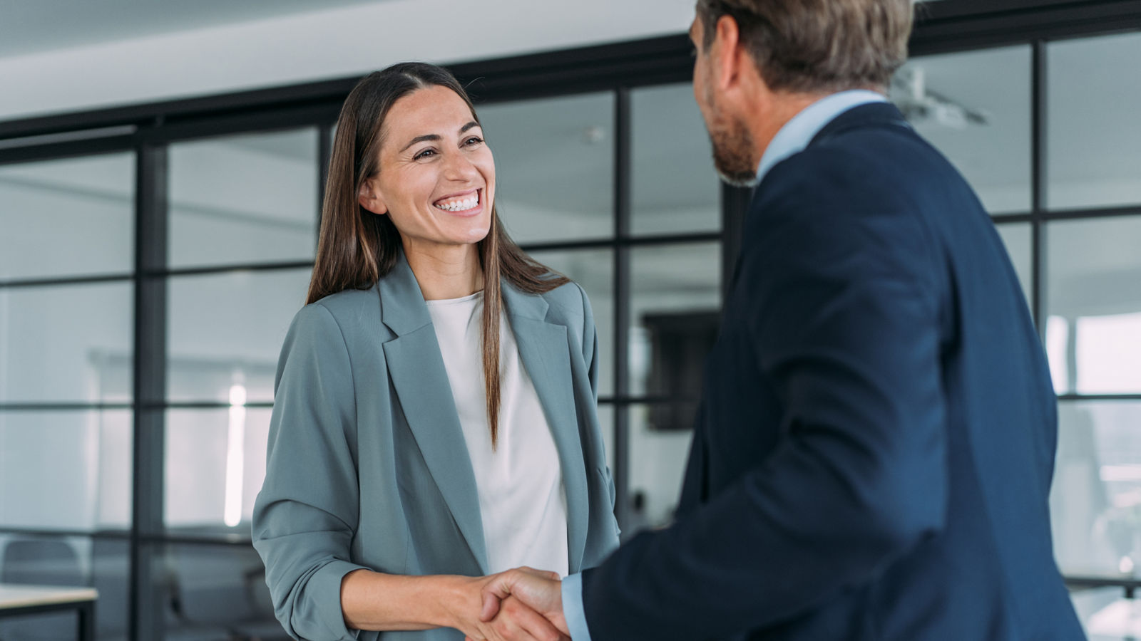 Business people shaking hands in modern office. 