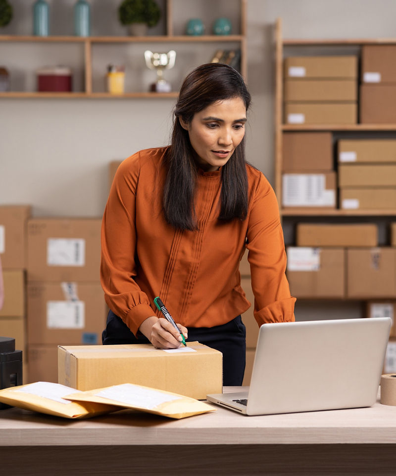 Small business owner using laptop in inventory room