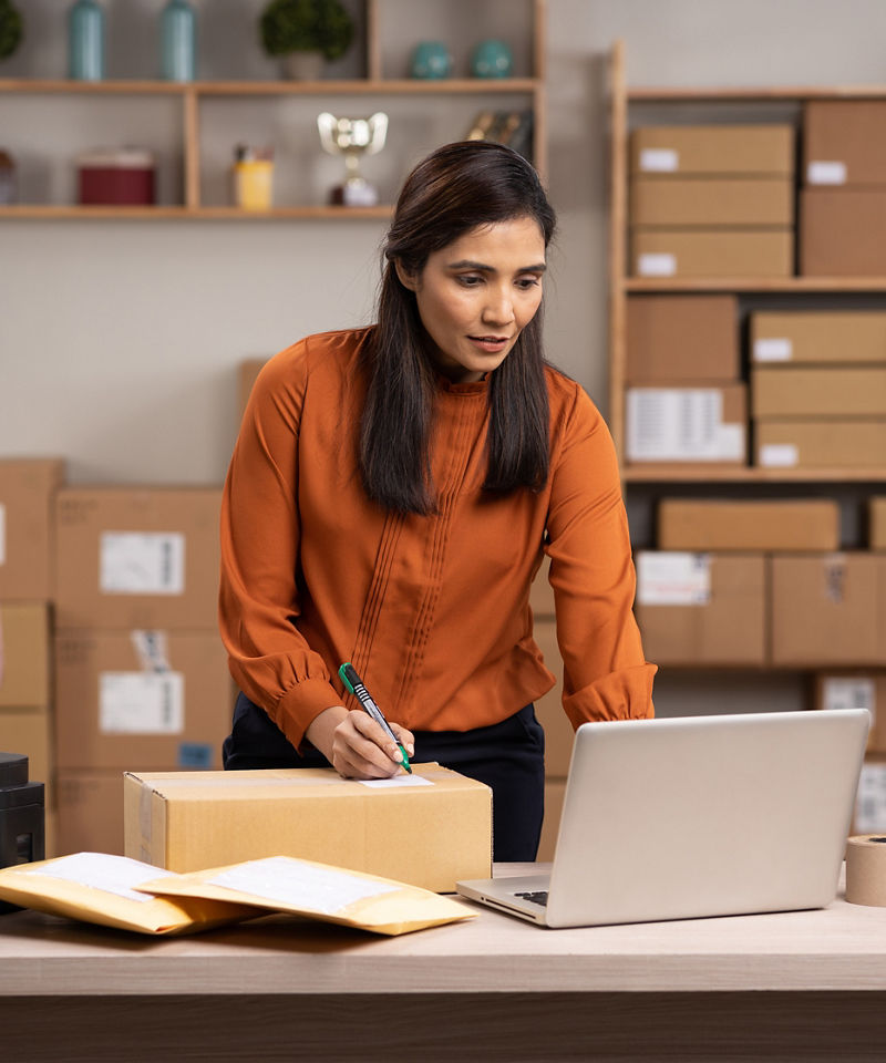 Small business owner using laptop in inventory room