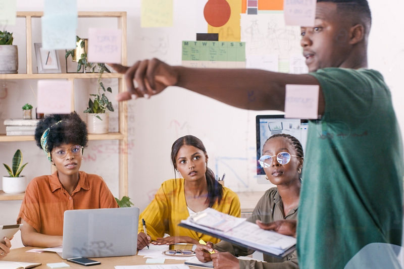 Business meeting, sticky note and planning people at marketing agency brainstorming ideas, schedule planner and time management workshop. Diversity team and creative manager glass wall presentation