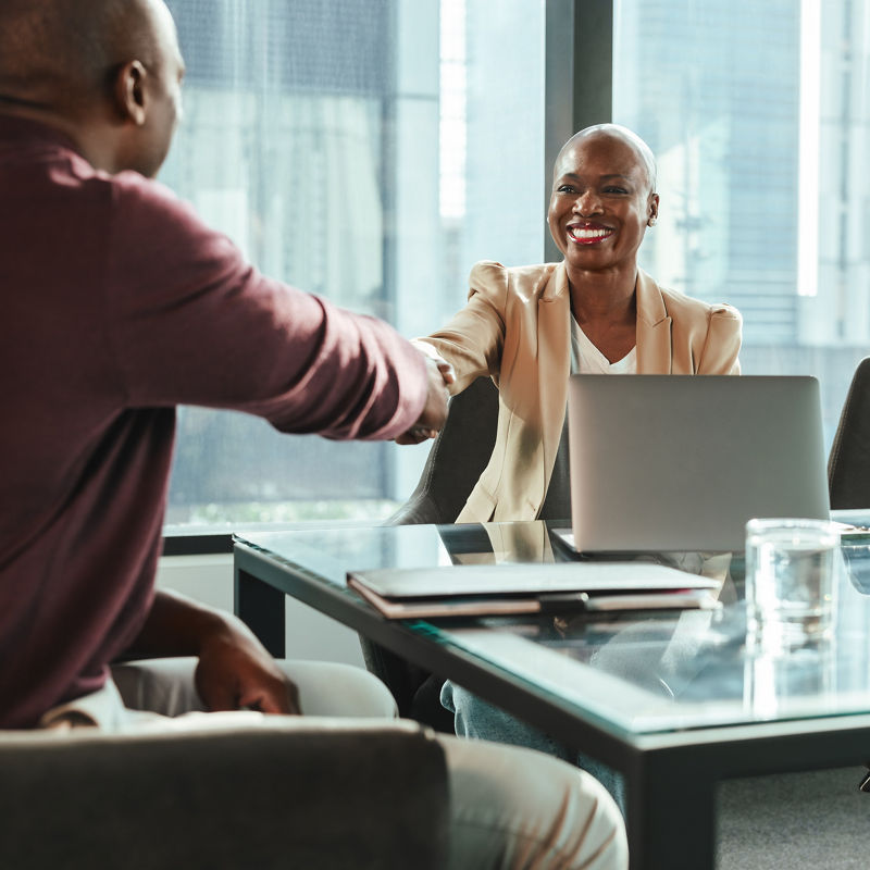 Business people in an office setting engage in a successful meeting, shaking hands.