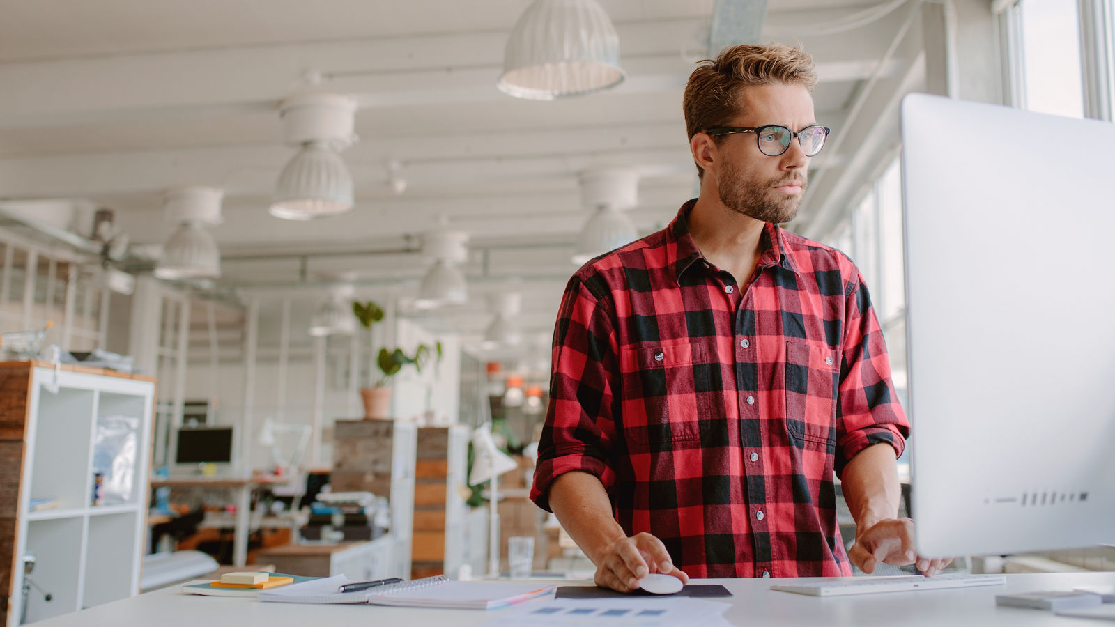 Young businessman in casual clothes at modern startup business office space, working on desktop computer.