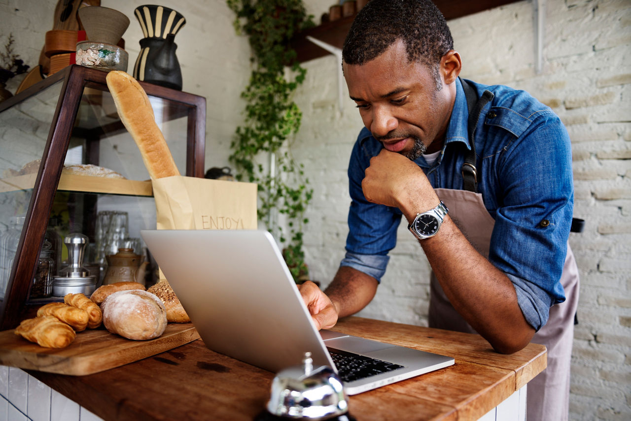 Man using laptop for online business order at bakehouse