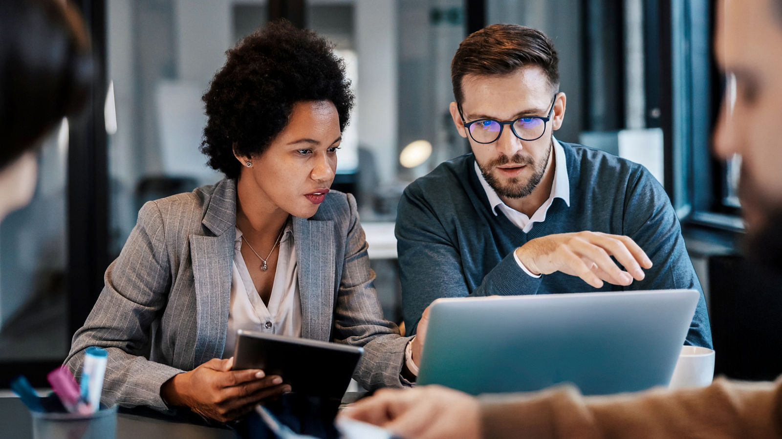 A man and woman looking at laptop discussing work