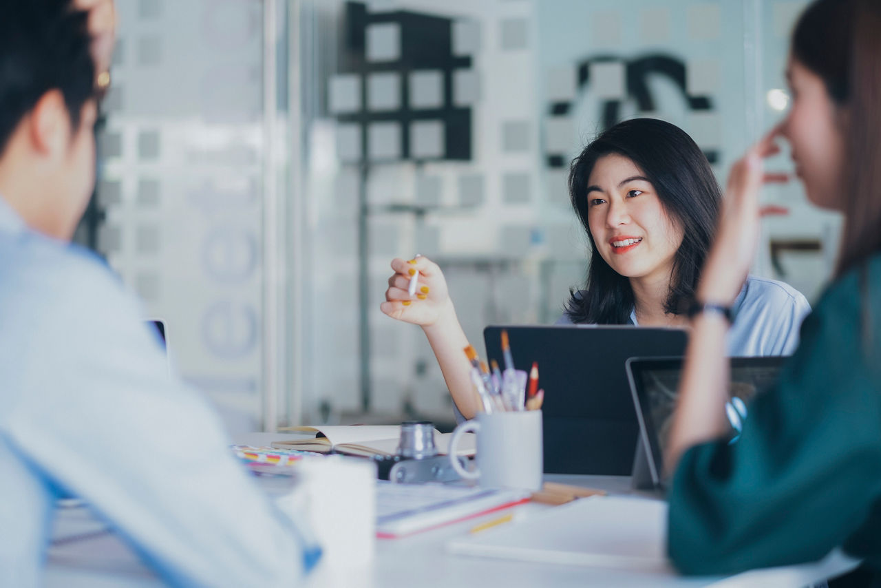 YOUNG WOMAN USING SMART PHONE WHILE SITTING IN OFFICE