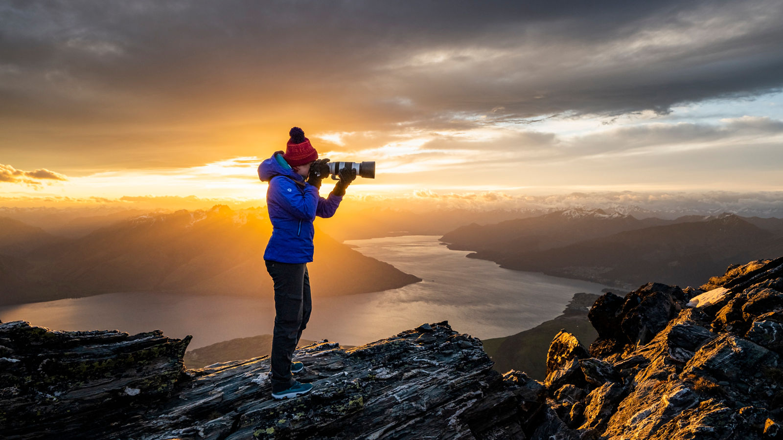 FULL LENGTH OF MAN STANDING ON ROCK AT SUNSET