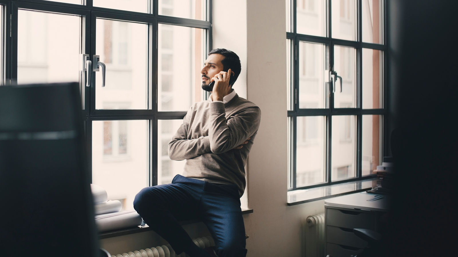 FULL LENGTH OF WOMAN USING PHONE WHILE SITTING IN WINDOW