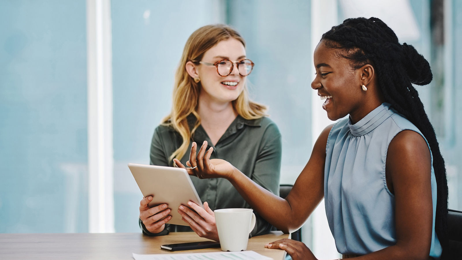 Two confident businesswomen working together on a digital tablet in an office