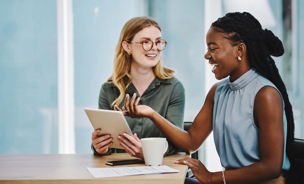 Two confident businesswomen working together on a digital tablet in an office