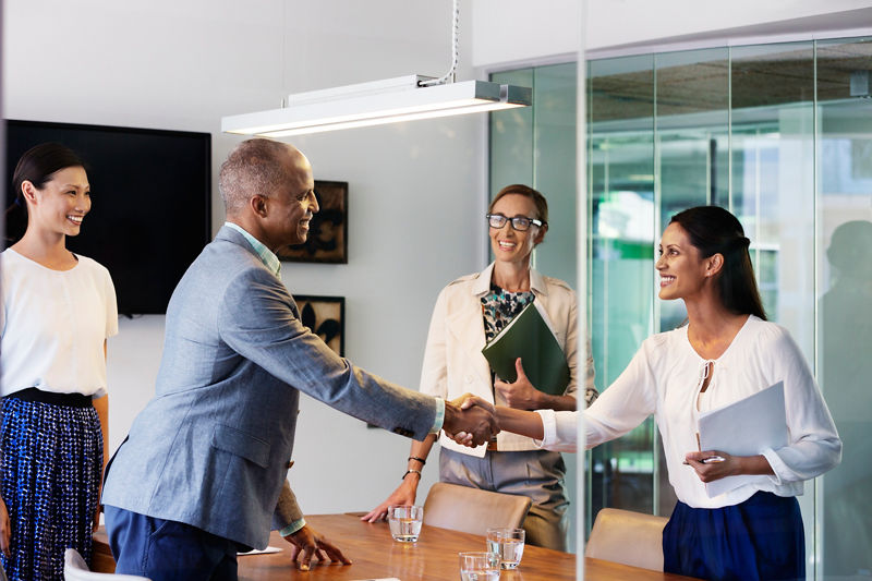 Happy business people shaking hands in board room at office