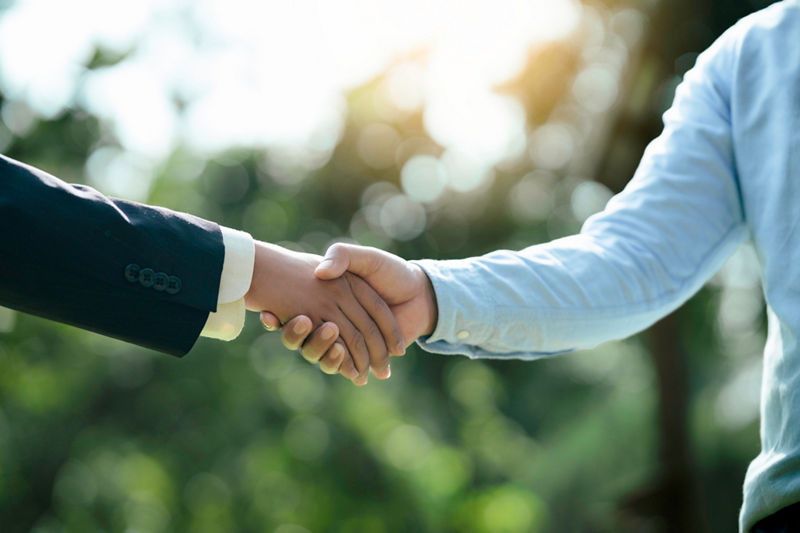Businessmen shaking hands outside