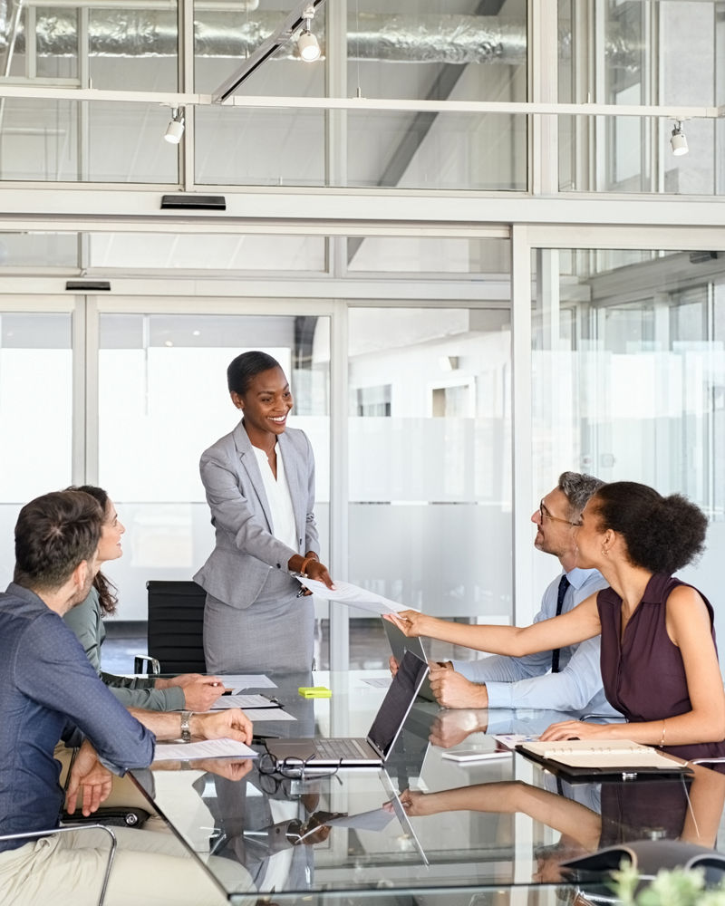 Business woman passing over documents to leader during business meeting
