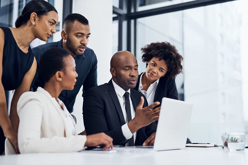 Group of people using a laptop together in a modern office
