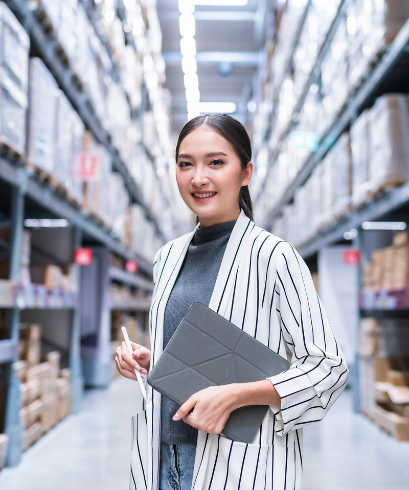 Woman business owner using digital tablet at distribution warehouse.