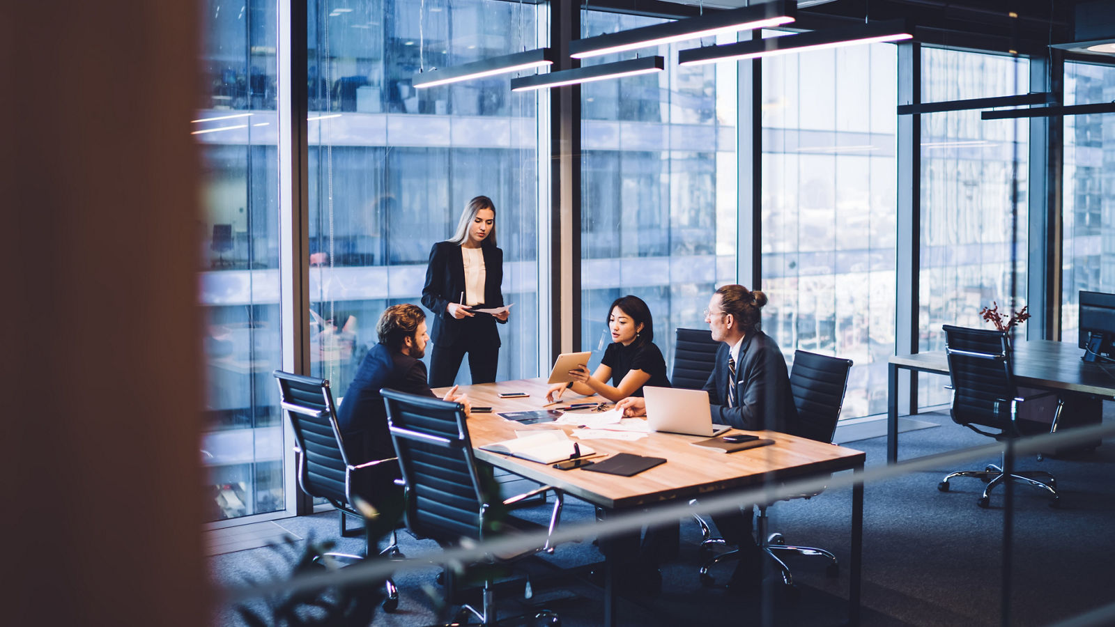 From above of group of diverse colleagues in formal clothing discussing business ideas while gathering at table in modern office and working together