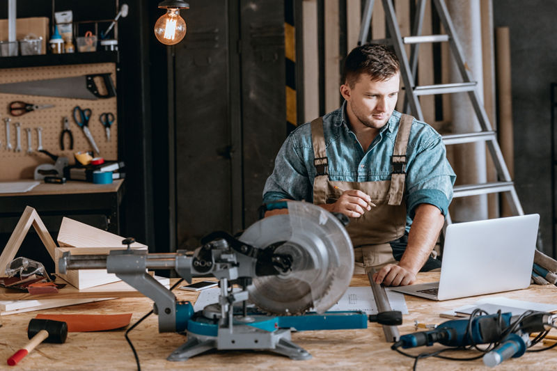 Carpenter focused on using laptop in workshop