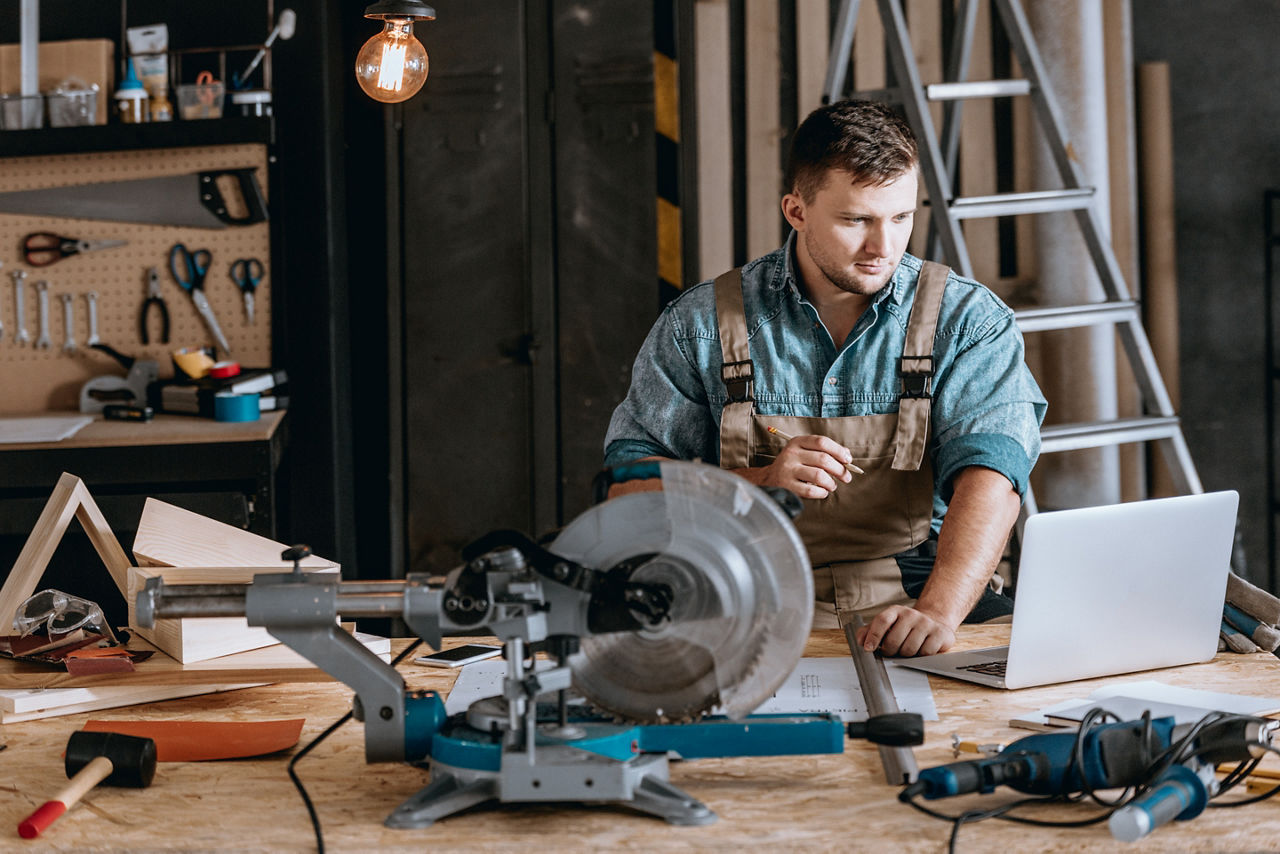 Carpenter focused on using laptop in workshop
