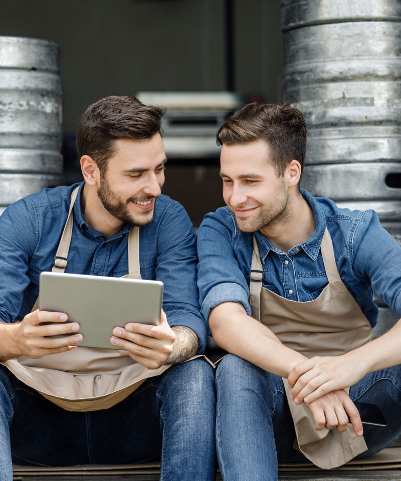 Small business owners of brewery looking at tablet together