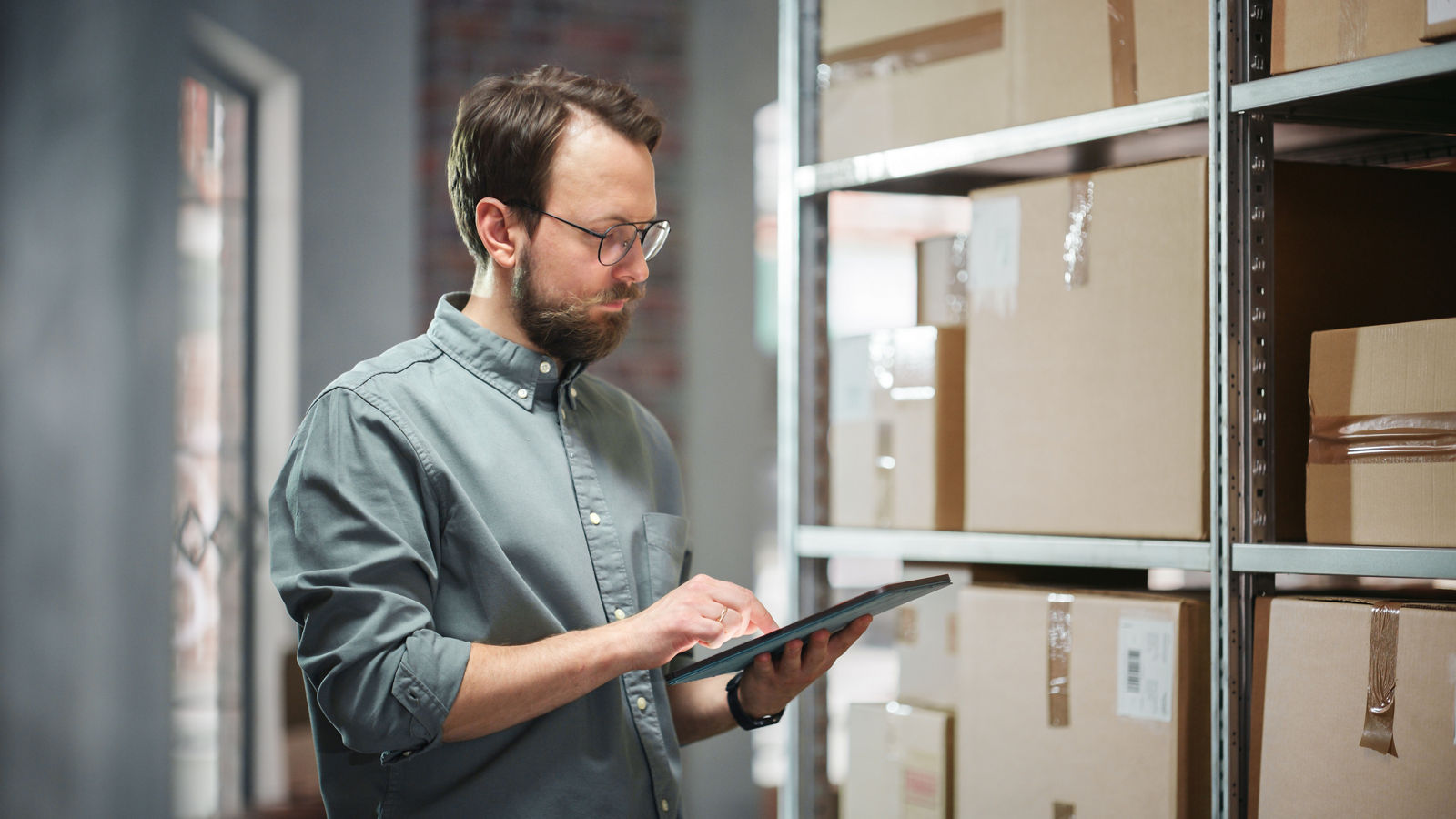 Man looking at tablet next to boxes and inventory