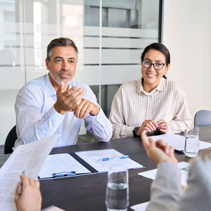 Diverse professional executive team working at meeting in office. Mid aged business man manager leader talking to board people consulting partners investors discussing project management in teamwork.